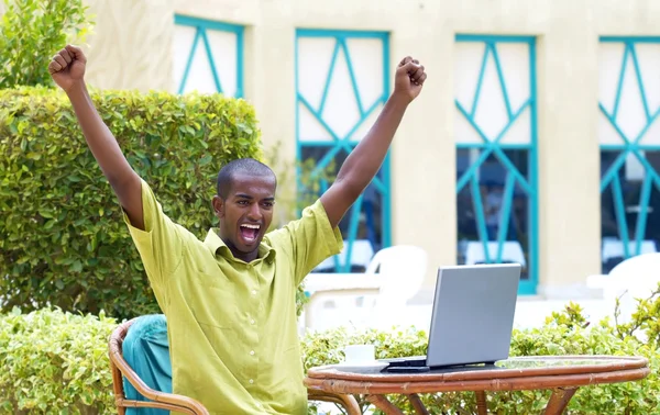 Молодий щасливий чоловік або студент з ноутбуком сидить за столом — стокове фото