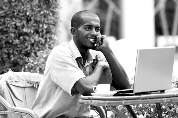 Giovane uomo felice o studente con computer portatile seduto a tavola — Foto Stock