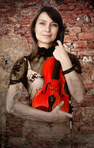 Beautiful female violinist with violin on the grunge background — Stock Photo, Image