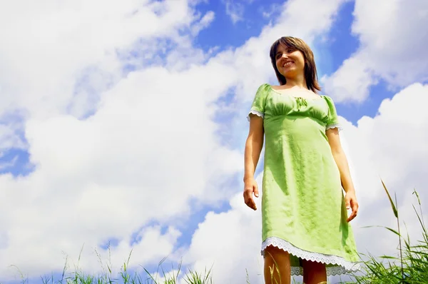 Mujer feliz en el cielo azul y el verde césped fondo — Stockfoto