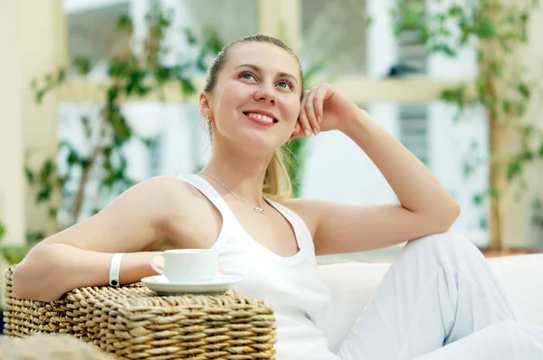 Glad kvinna i vitt med kopp kaffe eller te på sovrum — Stockfoto