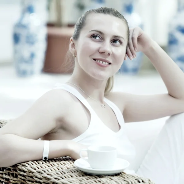 Glad kvinna i vitt med kopp kaffe eller te på sovrum — Stockfoto