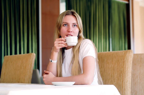 Glad kvinna i vitt med kopp kaffe eller te. — Stockfoto