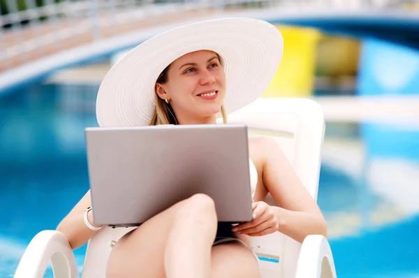 Jonge vrouwen ontspannen in de buurt van waterpool met laptop. — Stockfoto