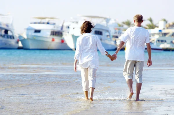 Weergave van gelukkige jonge paar wandelen op het strand, hand in hand. — Stockfoto