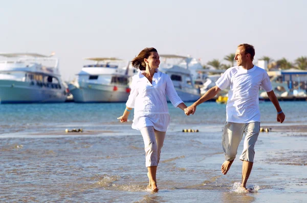 Вид щасливої молодої пари, що йде на пляжі, тримаючись за руки . — стокове фото