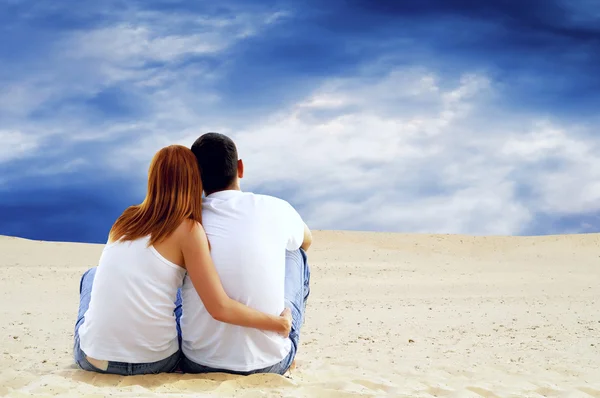Молода пара сидить у пустелі в сонячний день — стокове фото