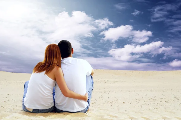 Junges Paar sitzt an sonnigem Tag in der Wüste — Stockfoto