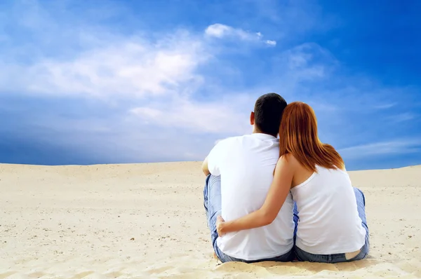 Jeune couple assis dans le désert par temps ensoleillé — Photo