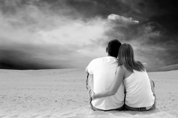 Giovane coppia seduta nel deserto nella giornata di sole — Foto Stock
