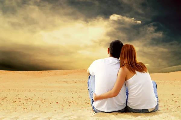 年轻夫妇座位在沙漠中阳光灿烂的日子 — 图库照片