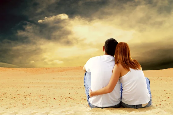 年轻夫妇座位在沙漠中阳光灿烂的日子 — 图库照片
