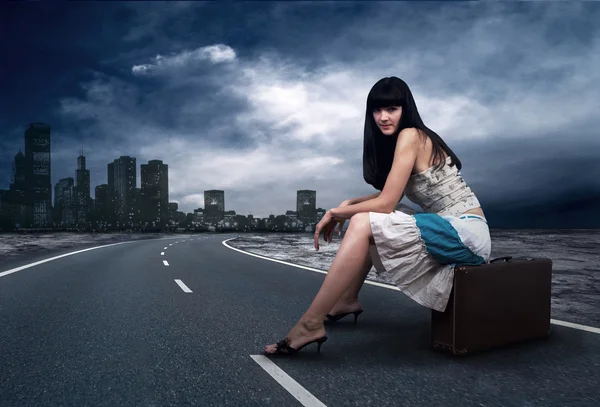 Joven mujer esperando en la carretera con su equipaje vintage —  Fotos de Stock