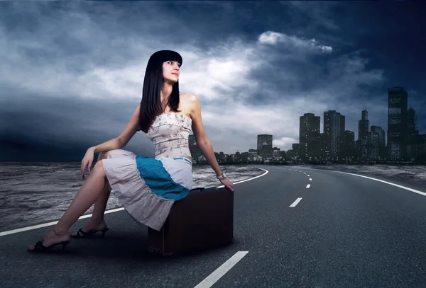 Ung kvinna väntar på väg med hennes vintage bagage — Stockfoto