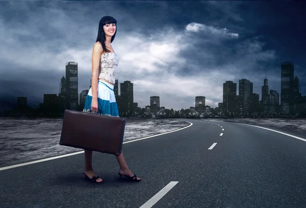 Молодая женщина ждет на дороге со своим винтажным багажом — стоковое фото