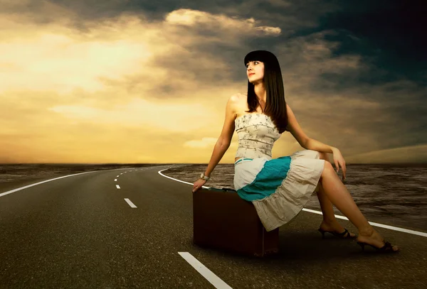 Mladá žena čekající na silnici s její vinobraní zavazadla — Stock fotografie