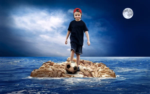 Kind met soccerball op het eiland in zee. — Stockfoto