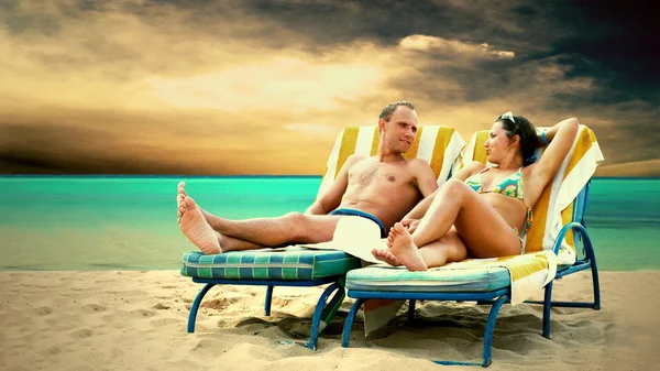 Вид сзади пары, отдыхающей на пляже на шезлонге — стоковое фото