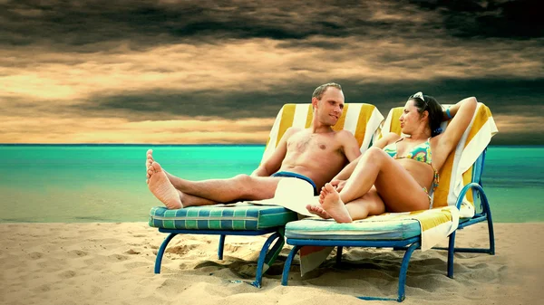 Вид сзади пары, отдыхающей на пляже на шезлонге — стоковое фото