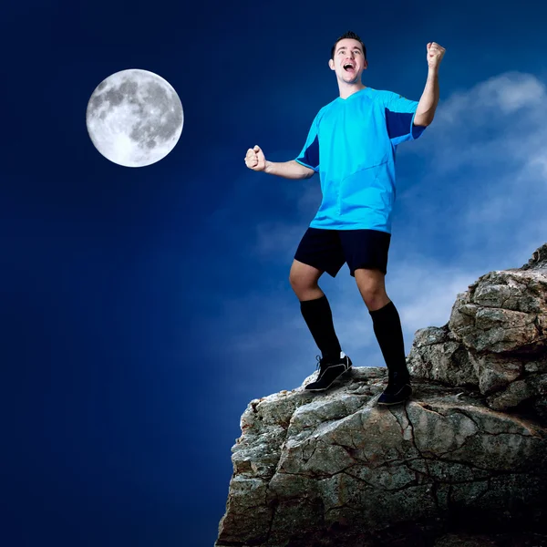 Футболист на вершине горы в лунную ночь — стоковое фото