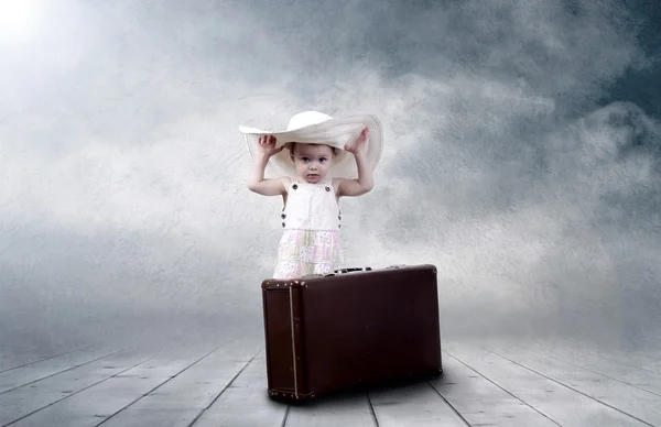 Маленькая девочка сидит на улице на винтажном багаже — стоковое фото