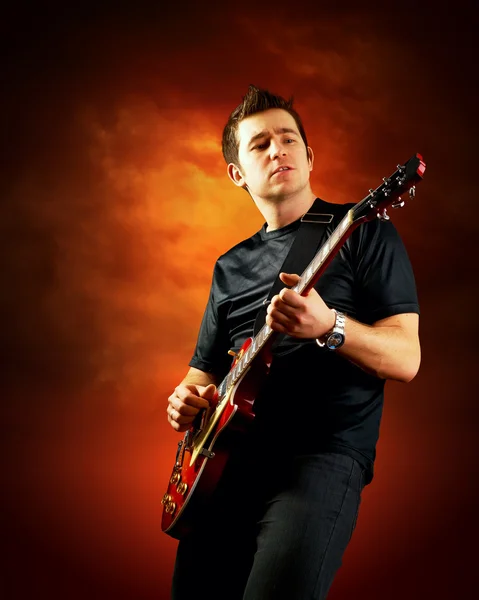 Rock guitarist play on the electric guitar, orange sky backgroun — Stock Photo, Image