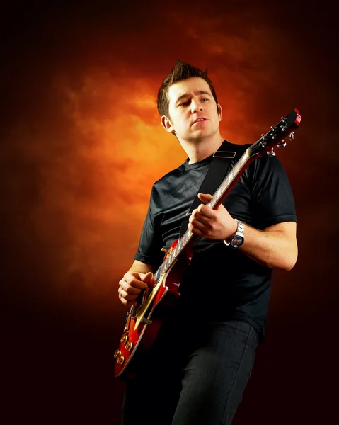 Rockový kytarista hrát na elektrickou kytaru, oranžová obloha poza — Stock fotografie