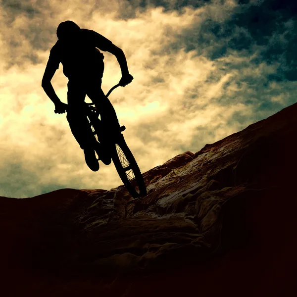 La silueta de un hombre en moto de montaña, puesta de sol Imagen De Stock