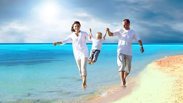 Vista della giovane famiglia felice che si diverte sulla spiaggia Foto Stock