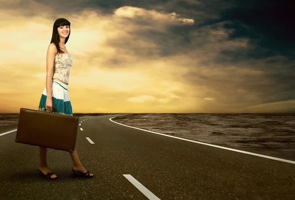 Молодая женщина ждет на дороге со своим винтажным багажом Стоковое Изображение