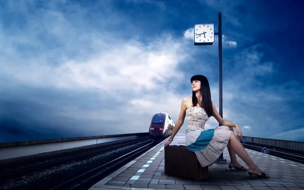 Дівчина чекає потяг на платформі залізничного вокзалу Стокове Фото