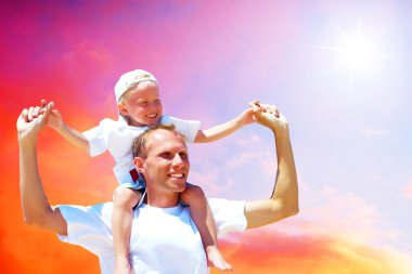 Joyful father giving piggyback ride to his son against a sky bac clipart