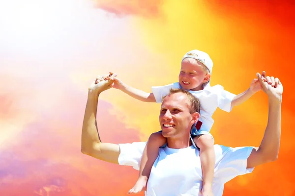 Gioioso padre che dà cavalcata a suo figlio contro un bac cielo — Foto Stock