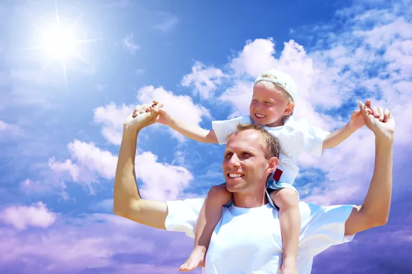 Alegre padre dando paseo a cuestas a su hijo contra un bac cielo —  Fotos de Stock
