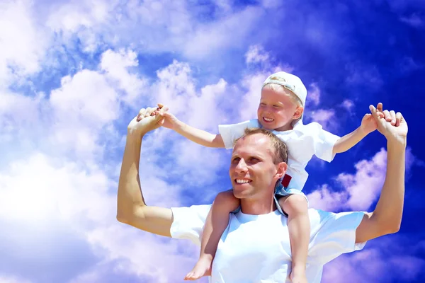 Χαρούμενη πατέρα δίνοντας piggyback βόλτα στον γιο του ουρανό bac — Φωτογραφία Αρχείου