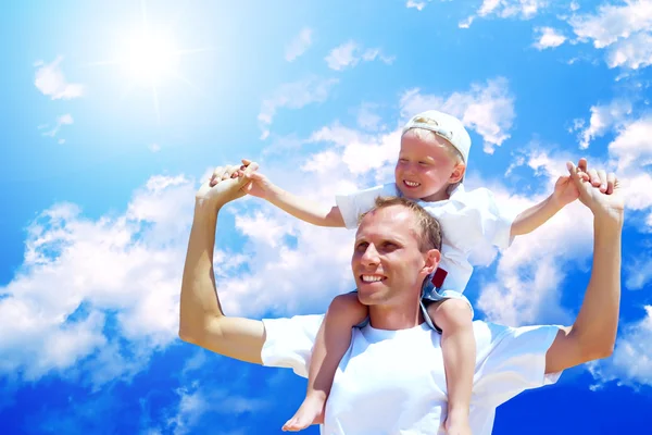 Freudiger Vater gibt seinem Sohn Huckepack-Fahrt gegen den Himmel — Stockfoto