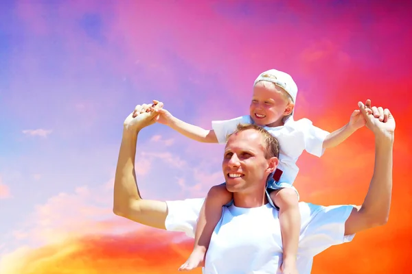 Glædelig far giver piggyback tur til sin søn mod en himmel bac - Stock-foto