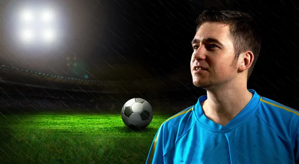 Портрет футболиста на поле под ночным дождем — стоковое фото
