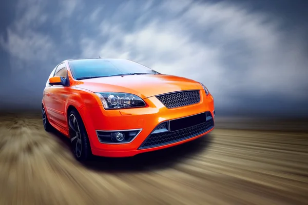 Оранжевый спорткар на дороге — стоковое фото