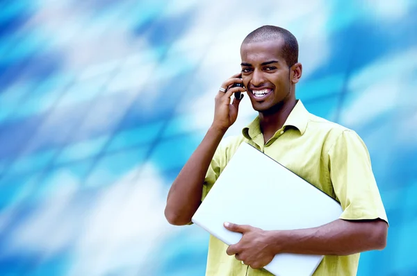 Jeune homme heureux ou étudiant avec ordinateur portable et téléphone sur l'entreprise — Photo