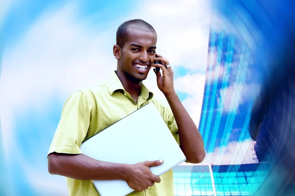 Jovem homem feliz ou estudante com laptop e telefone no negócio — Fotografia de Stock