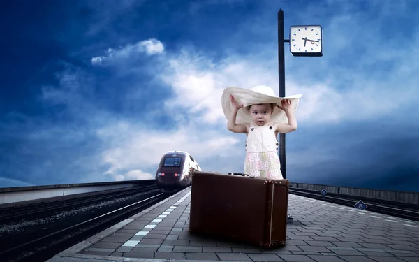 Маленькая девочка сидит на винтажном багаже на железнодорожной платформе — стоковое фото
