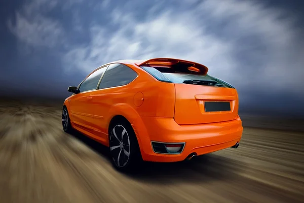 Оранжевый спорткар на дороге — стоковое фото