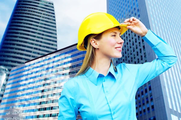 Ung arkitekt-kvinna som bär en skyddande hjälm stående på th — Stockfoto