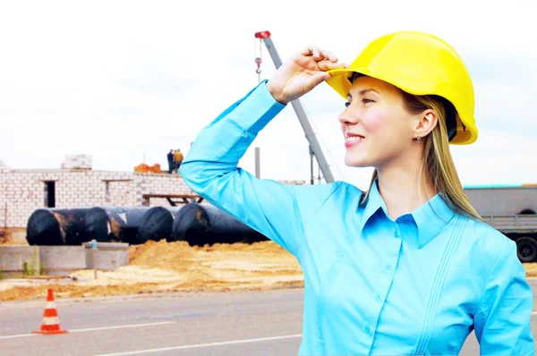 Ung arkitekt-kvinna som bär en skyddande hjälm stående på th — Stockfoto