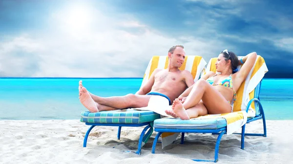Vista trasera de una pareja en una tumbona relajante en la playa — Foto de Stock