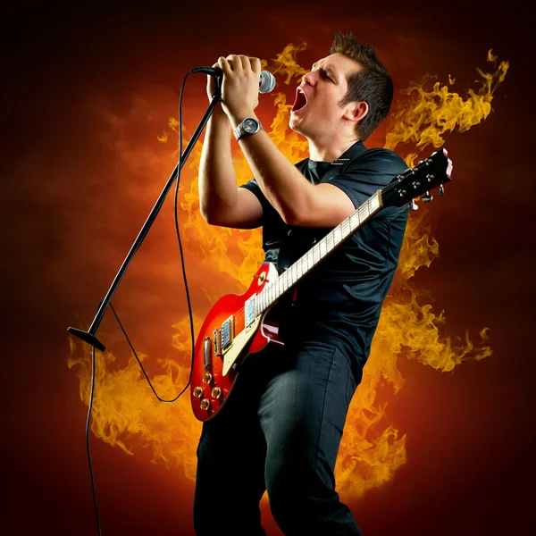 Guitariste rock jouer sur la guitare électrique autour des flammes de feu — Photo