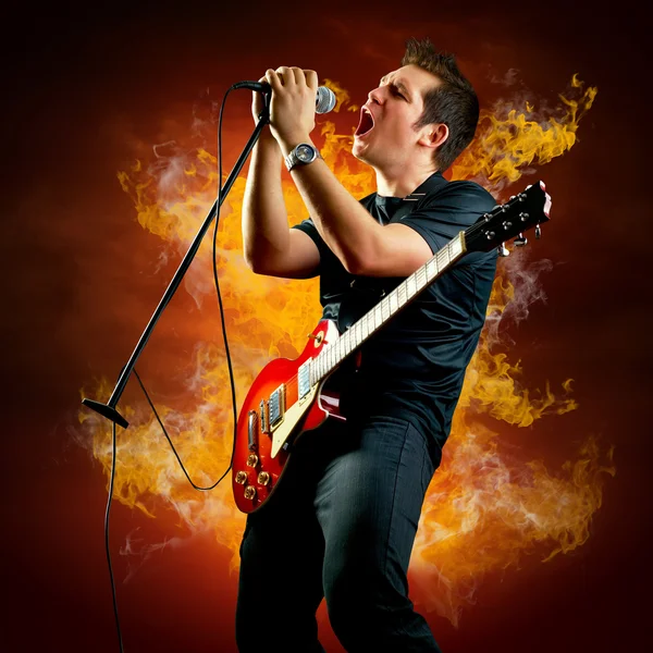 Rock guitarist play on the electric guitar around fire flames — Stock Photo, Image