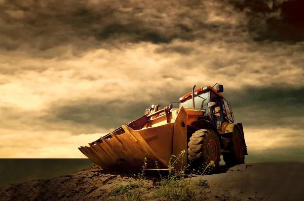 Gelber Traktor am goldenen Himmel des Sonnenaufgangs — Stockfoto
