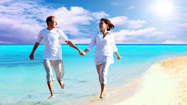 快乐对年轻夫妇在沙滩上散步手牵着手的视图. — 图库照片